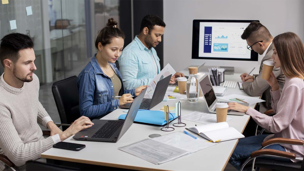 Team arbeitet in modernem Büro am Laptop