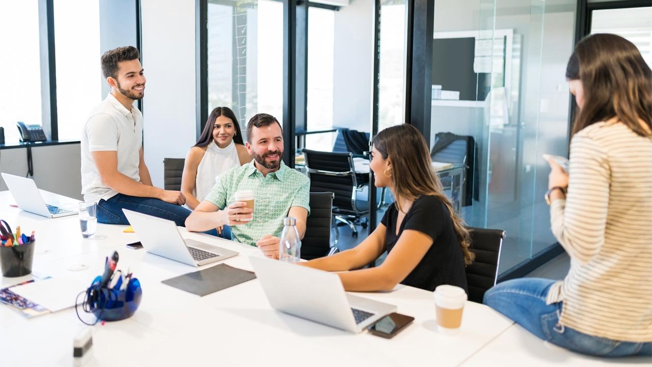 Büroteam bei einer informellen Besprechung mit Laptops